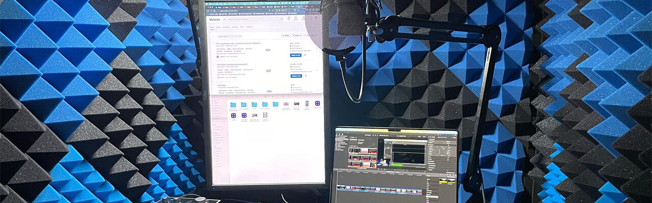 Voice over booth with a laptop, monitor, microphone, and absorptive foam on the walls.